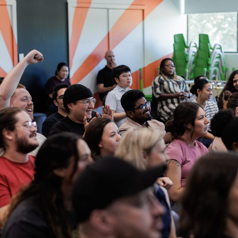 The cohort filling the room — laughing, hands up, locked in